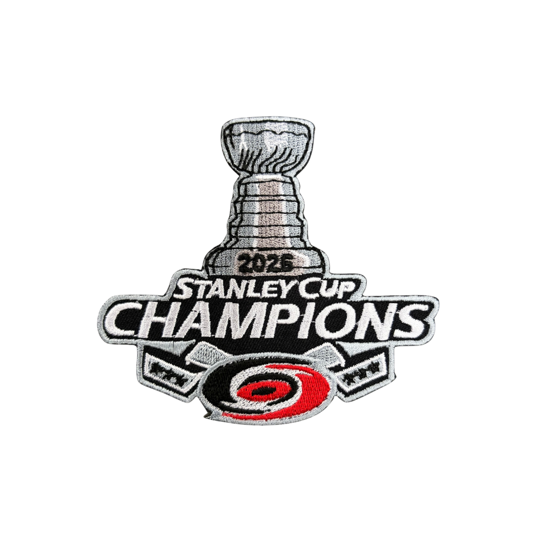 An embroidered patch celebrating the 2025 Stanley Cup Champions, featuring the Stanley Cup trophy, the text '2026 STANLEY CUP CHAMPIONS,' and the Carolina Hurricanes logo at the bottom.