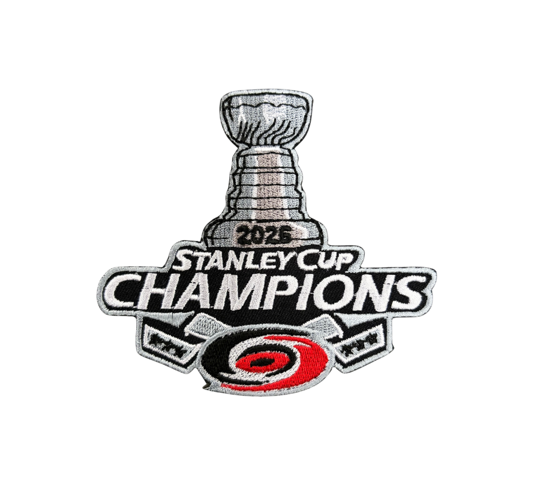 An embroidered patch celebrating the 2025 Stanley Cup Champions, featuring the Stanley Cup trophy, the text '2026 STANLEY CUP CHAMPIONS,' and the Carolina Hurricanes logo at the bottom.